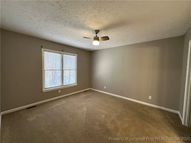 an empty room with windows and ceiling fan