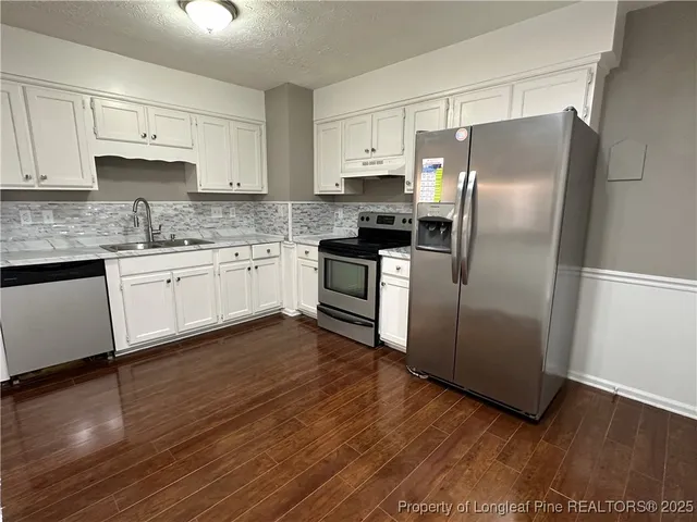 a kitchen with granite countertop stainless steel appliances a sink and refrigerator
