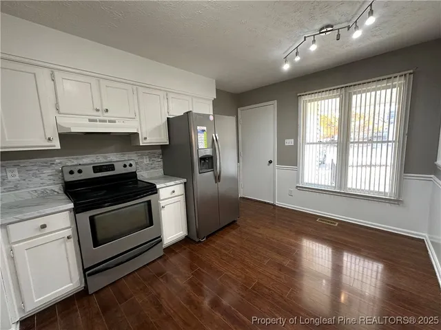 a kitchen with granite countertop a refrigerator stove and wooden floor