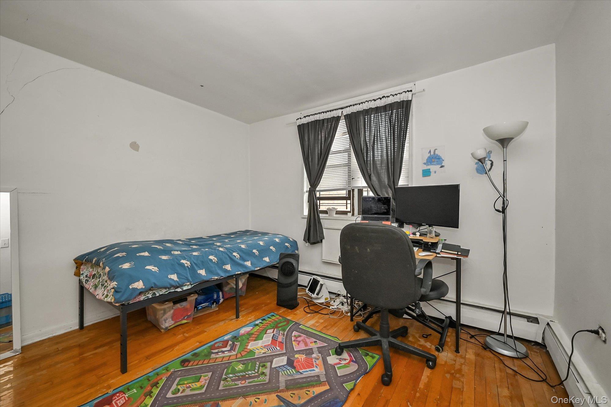 99-30 59th Avenue, Unit 6G Queens, NY 11368 - Photo 19 of 24 Bedroom featuring a desk, a baseboard heating unit, and hardwood / wood-style floors