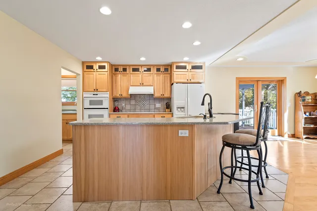 a kitchen with stainless steel appliances kitchen island granite countertop a table chairs sink and cabinets