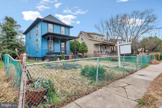 a view of a white house with a yard and table and chairs under an umbrella