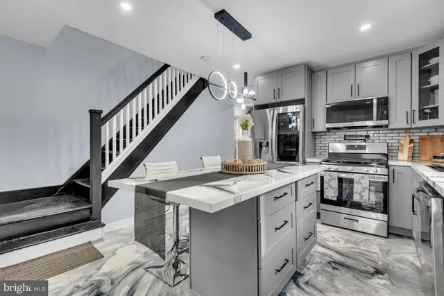 a kitchen with stainless steel appliances kitchen island granite countertop a stove a sink and a refrigerator