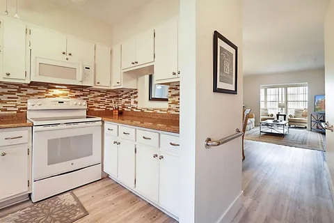 a kitchen with stainless steel appliances white cabinets and wooden floor