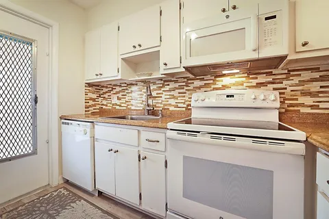 a kitchen with granite countertop a sink cabinets and stainless steel appliances