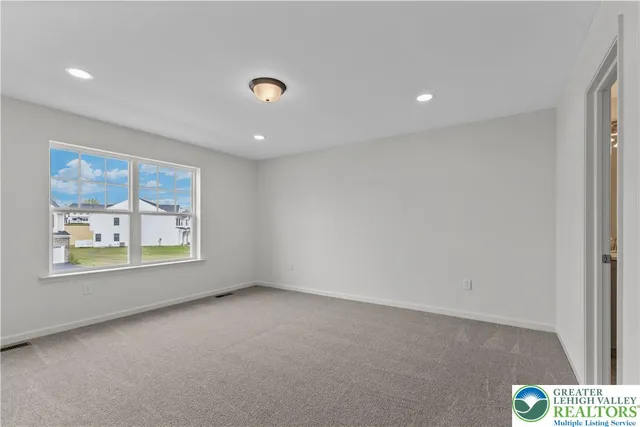 an empty room with windows and air conditioner vent