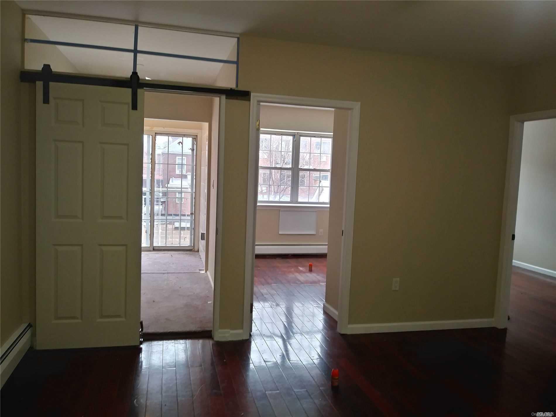 a view of a hallway with wooden floor and a window