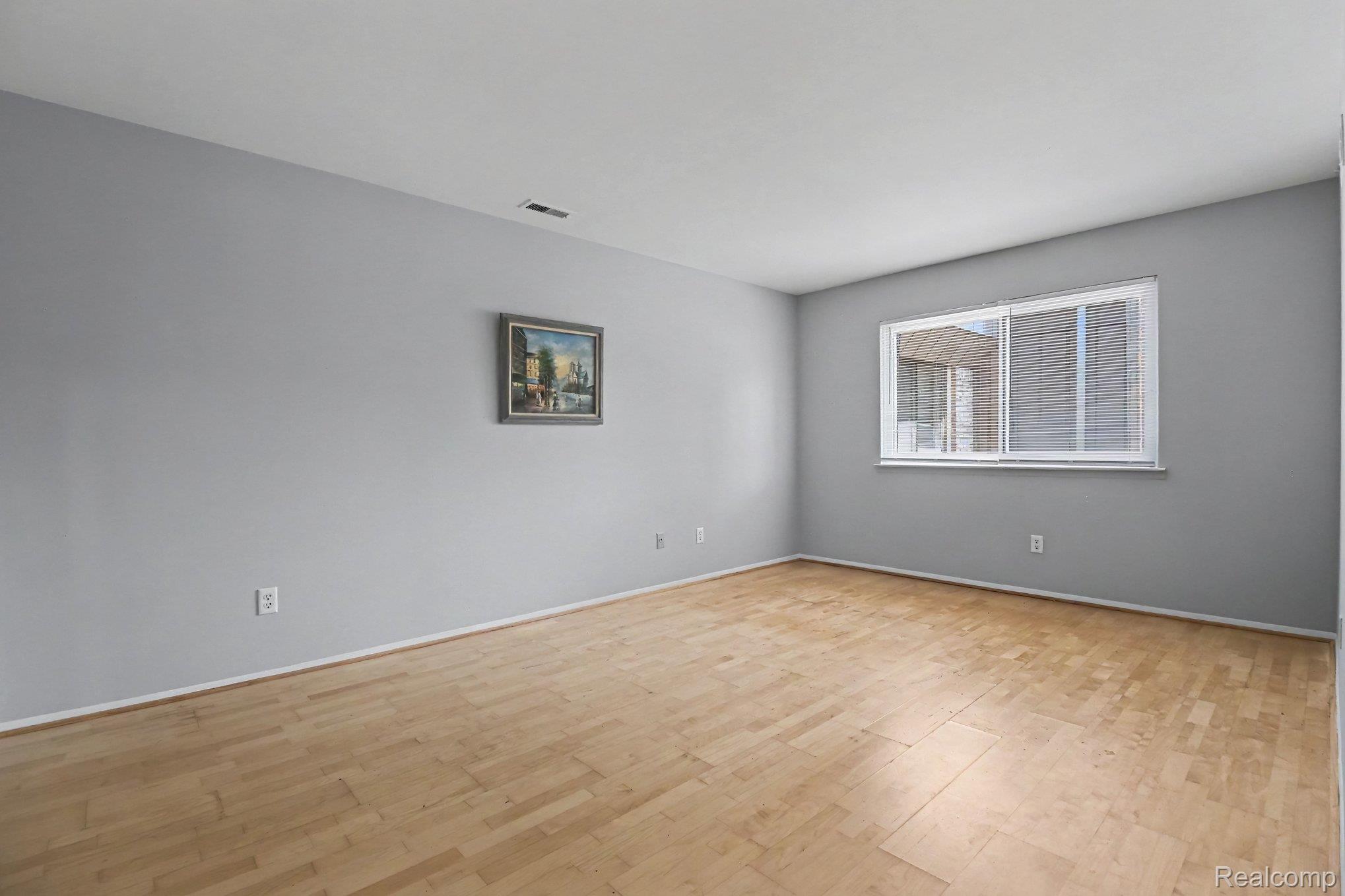 29890 West 12 Mile Road, Unit 907 Farmington, MI 48334 - Photo 12 of 18 Spacious room featuring wood-finish flooring, light gray walls, and a large window with white blinds