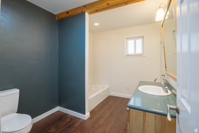 634 South 2100th Street West Vernal, UT 84078 - Photo 24 of 71 Bathroom featuring wood-finish flooring, a white toilet, a built-in bathtub with shower, a vanity with an integrated sink, and a framed mirror