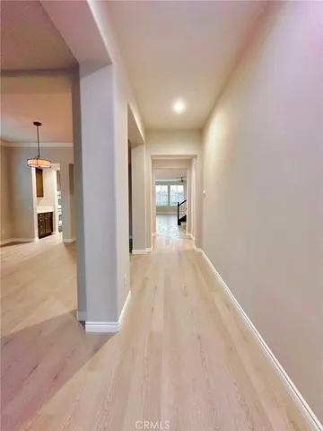 a view of a hallway with wooden floor and a bathroom