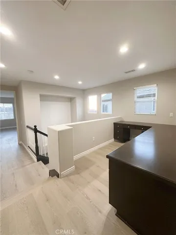 a view of an empty room with kitchen and window