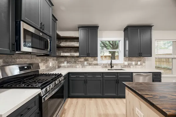a kitchen with stainless steel appliances granite countertop a stove microwave and sink