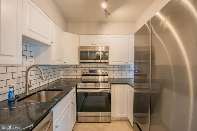 a kitchen with granite countertop a sink stainless steel appliances and cabinets