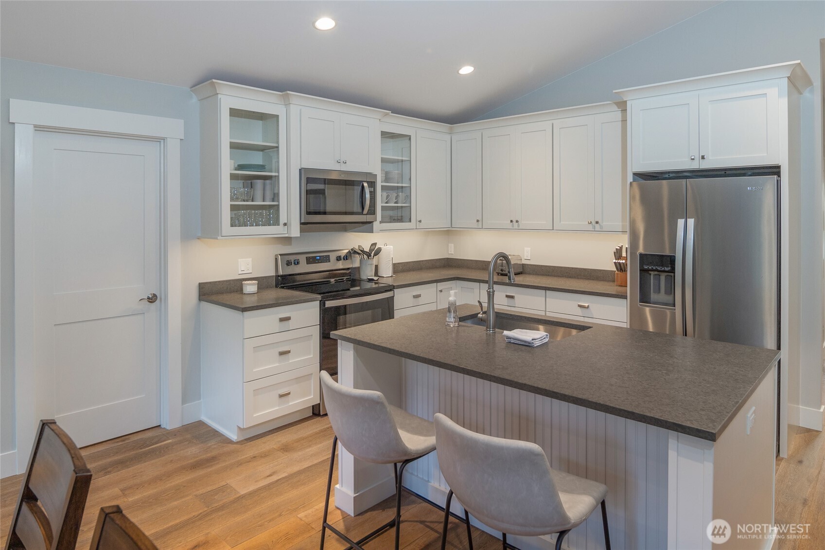 492 Finnegan Ridge, Unit 2 Friday Harbor, WA 98250 - Photo 9 of 29 a kitchen with stainless steel appliances granite countertop a table chairs sink refrigerator and cabinets