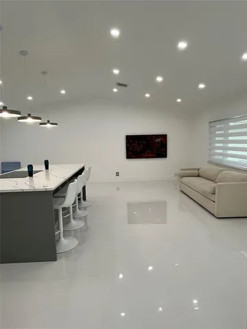 a large kitchen with a large counter top a sink stainless steel appliances and cabinets