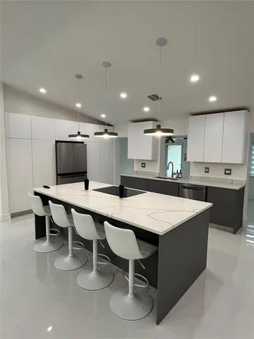 a kitchen with kitchen island a sink a stove and a refrigerator