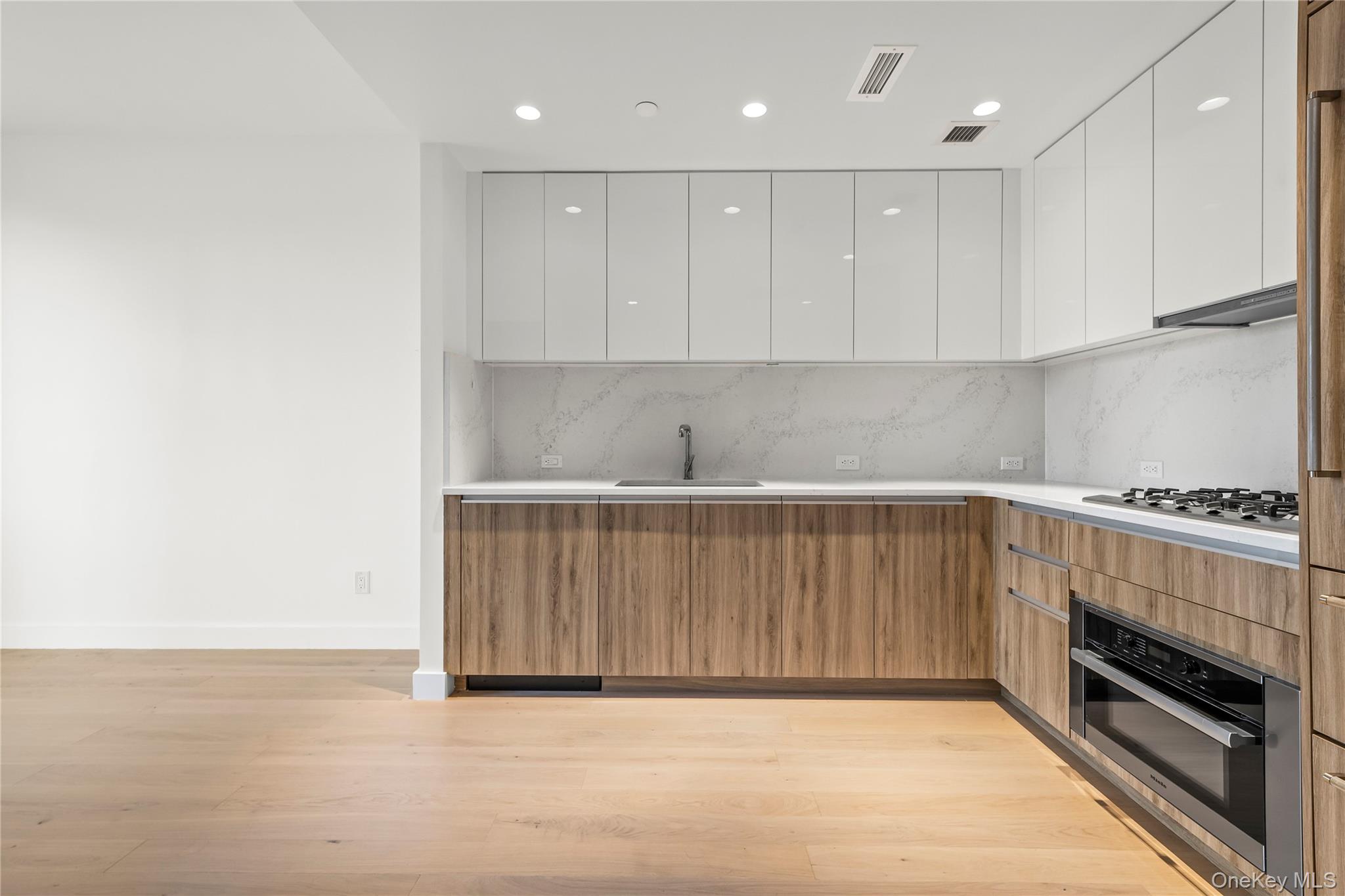 13618 Maple Avenue, Unit 5G Queens, NY 11355 - Photo 12 of 16 Kitchen featuring modern cabinets, white cabinetry, brown cabinetry, light wood finished floors, and oven