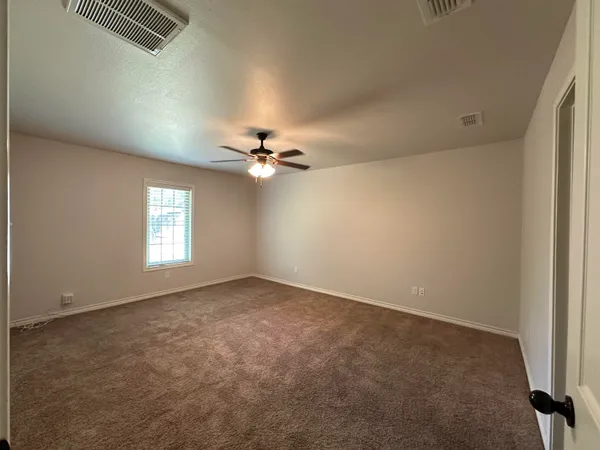 an empty room with windows and chandelier fan