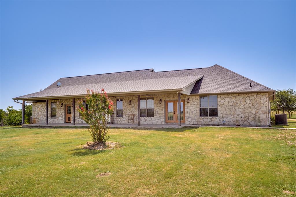 243 ROCK Court Decatur, TX 76234 - Photo 17 of 25 Stone exterior residence featuring a covered porch, multiple large windows, and a dark shingle roof