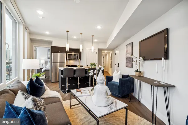 a living room with furniture a flat screen tv and kitchen view