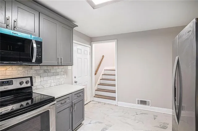 a kitchen with stainless steel appliances granite countertop a refrigerator and a stove top oven