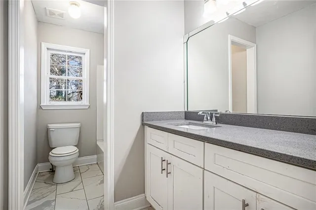 a bathroom with a granite countertop sink a toilet and a mirror