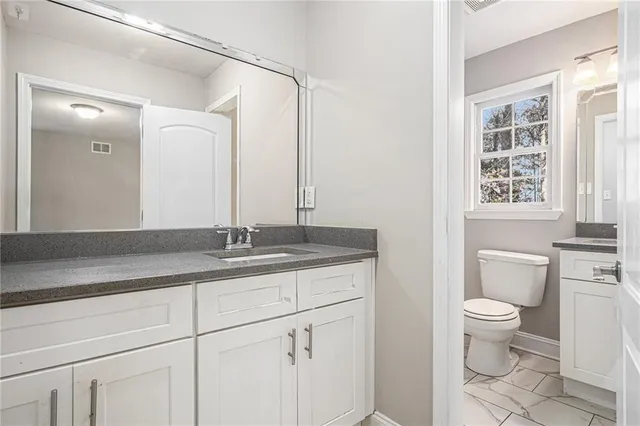 a bathroom with a granite countertop sink a toilet and a mirror