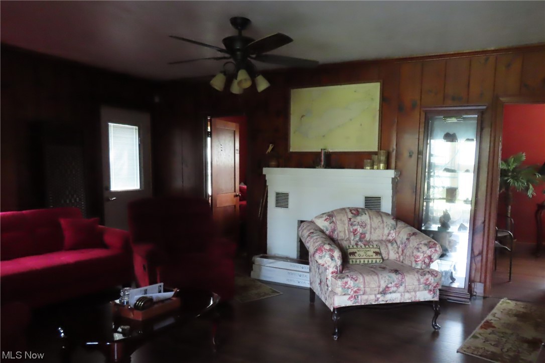 182 Harcourt Road Vermilion, OH 44089 - Photo 16 of 29 Living room with wooden walls, dark hardwood floors, a fireplace, and ceiling fan