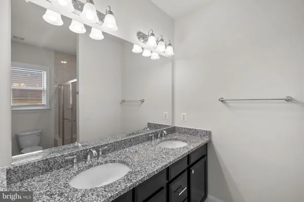 a bathroom with a granite countertop sink a light fixture and a mirror