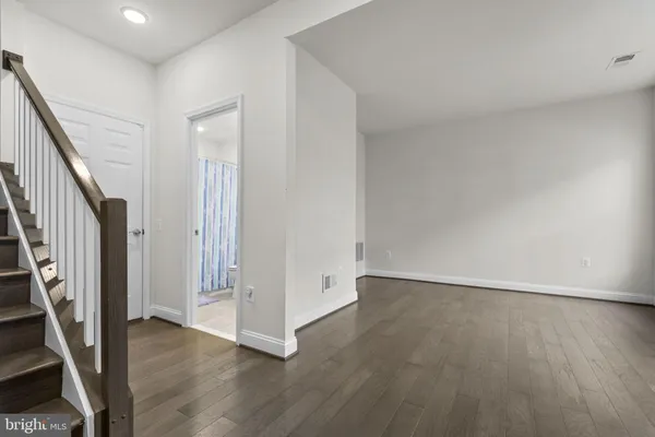 an empty room with wooden floor and staircase
