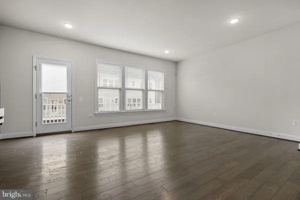 an empty room with wooden floor and windows with curtains