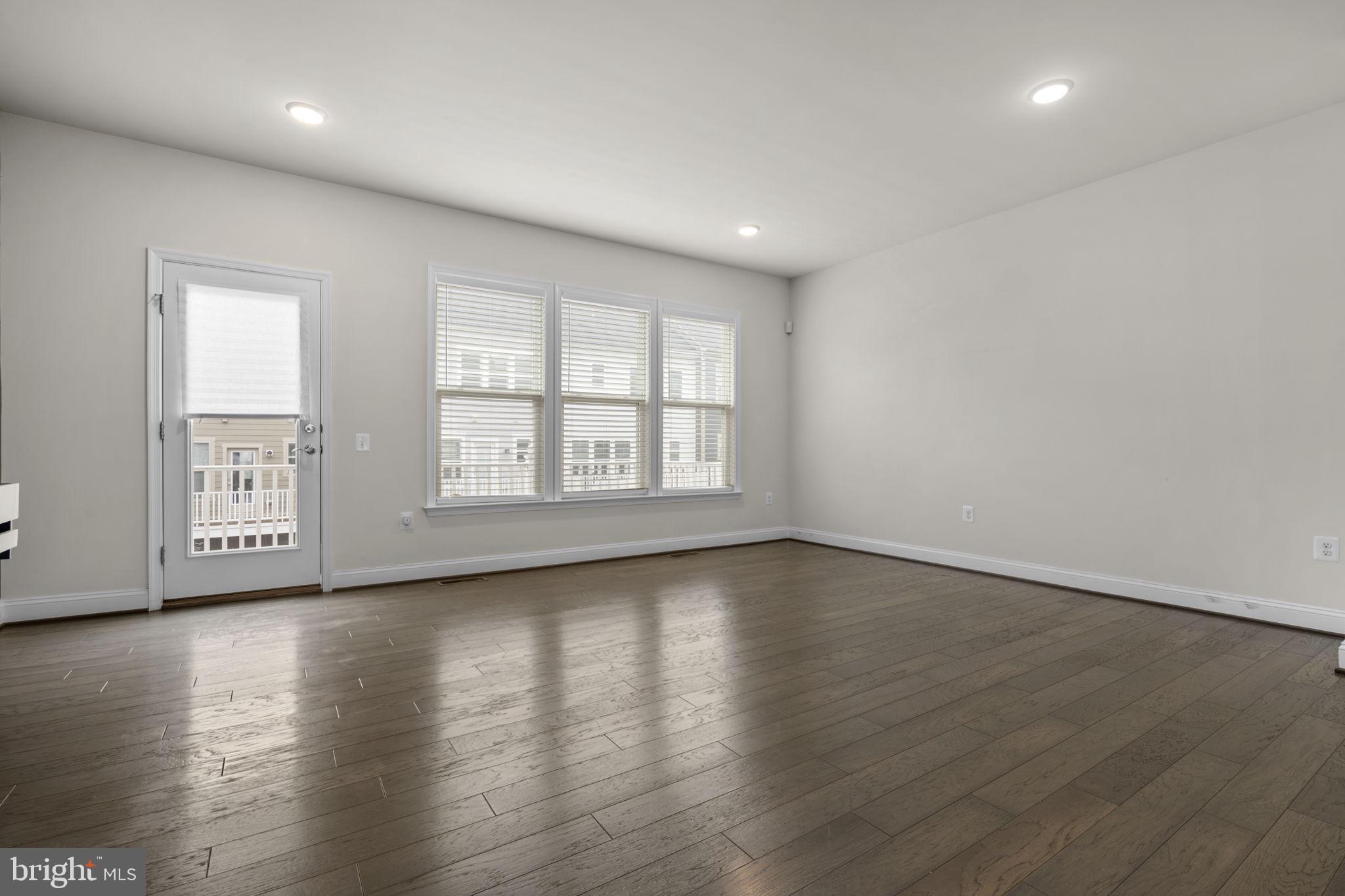 17357 Redshank Road Dumfries, VA 22026 - Photo 6 of 29 an empty room with wooden floor and windows with curtains