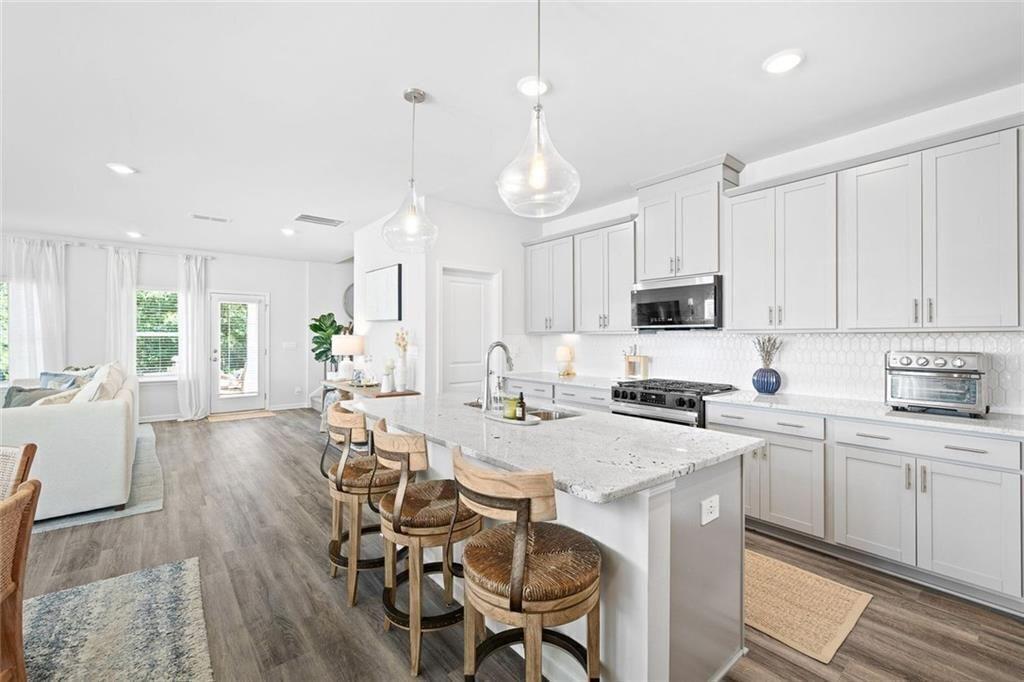 4167 Waratah Way Mableton, GA 30126 - Photo 5 of 32 a kitchen with stainless steel appliances a dining table chairs stove refrigerator and cabinets