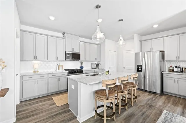 a kitchen with stainless steel appliances a dining table chairs stove refrigerator and cabinets