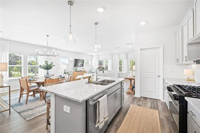 a open kitchen with stainless steel appliances granite countertop a sink stove and a refrigerator with wooden floor