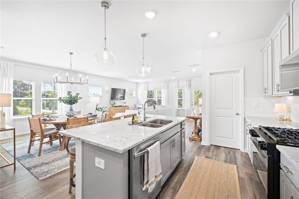 4167 Waratah Way Mableton, GA 30126 - Photo 9 of 32 a open kitchen with stainless steel appliances granite countertop a sink stove and a refrigerator with wooden floor