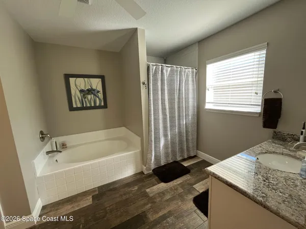 a bathroom with a granite countertop tub sink and mirror