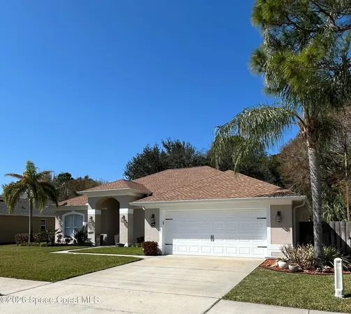a view of a white house next to a yard with palm trees