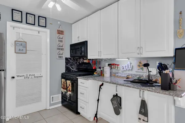 a kitchen with refrigerator a stove a sink and white cabinets