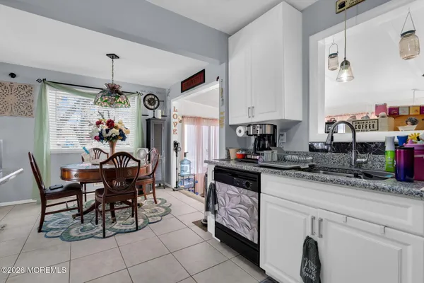 a kitchen with kitchen island granite countertop lots of white furniture a refrigerator and a sink