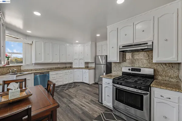 a kitchen with stainless steel appliances white cabinets and wooden floors