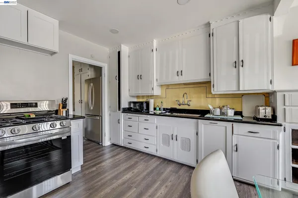 a kitchen with granite countertop white cabinets and stainless steel appliances