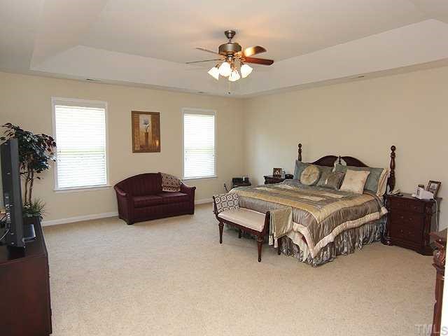 131 Locke Woods Road Raleigh, NC 27603 - Photo 7 of 18 a spacious bedroom with a bed and a chandelier