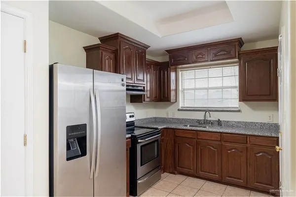 a kitchen with granite countertop stainless steel appliances a refrigerator and a sink