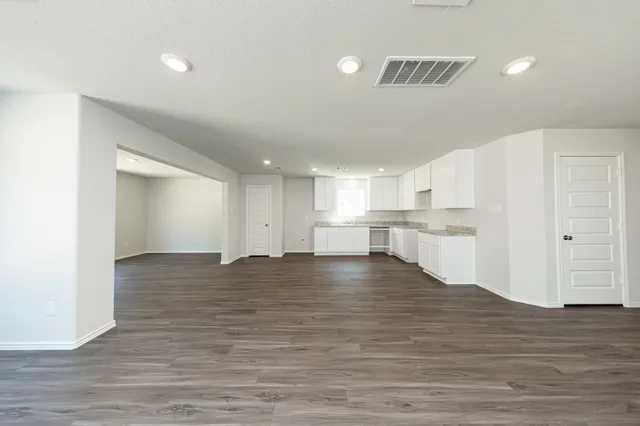 a view of kitchen and empty room with wooden floor