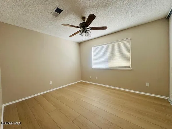 an empty room with windows and fan