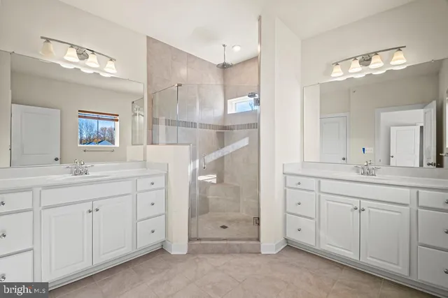 a spacious bathroom with a double vanity sink a mirror a and a shower