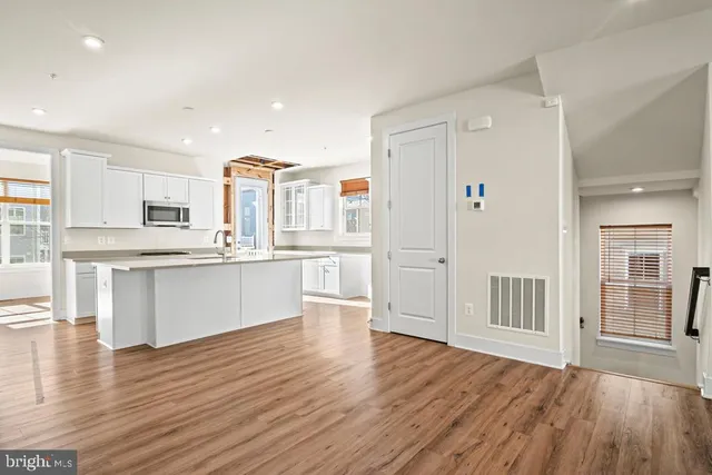 a large kitchen with a center island wooden floor and stainless steel appliances
