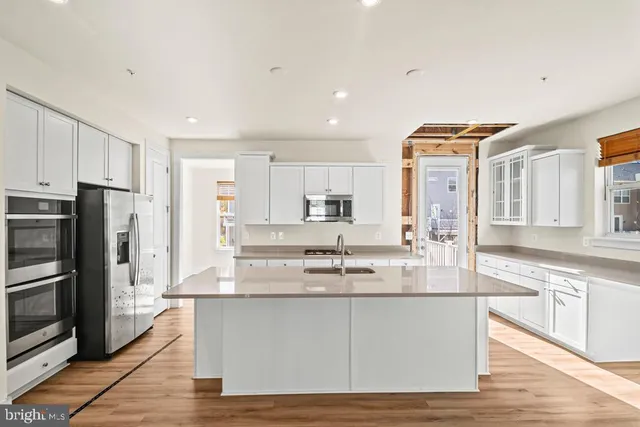a large kitchen with granite countertop a large counter top stainless steel appliances and cabinets
