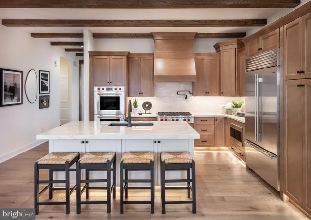 a kitchen with stainless steel appliances kitchen island granite countertop a table chairs sink and cabinets